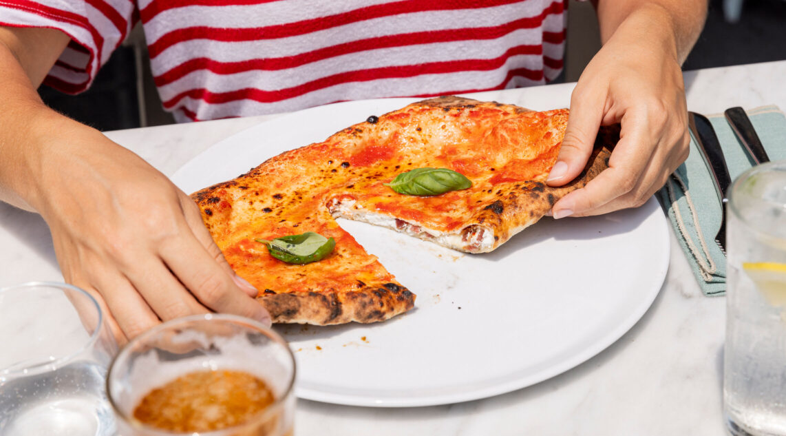 zwei Hände reißen eine frische neapolitanische Calzone auseinander