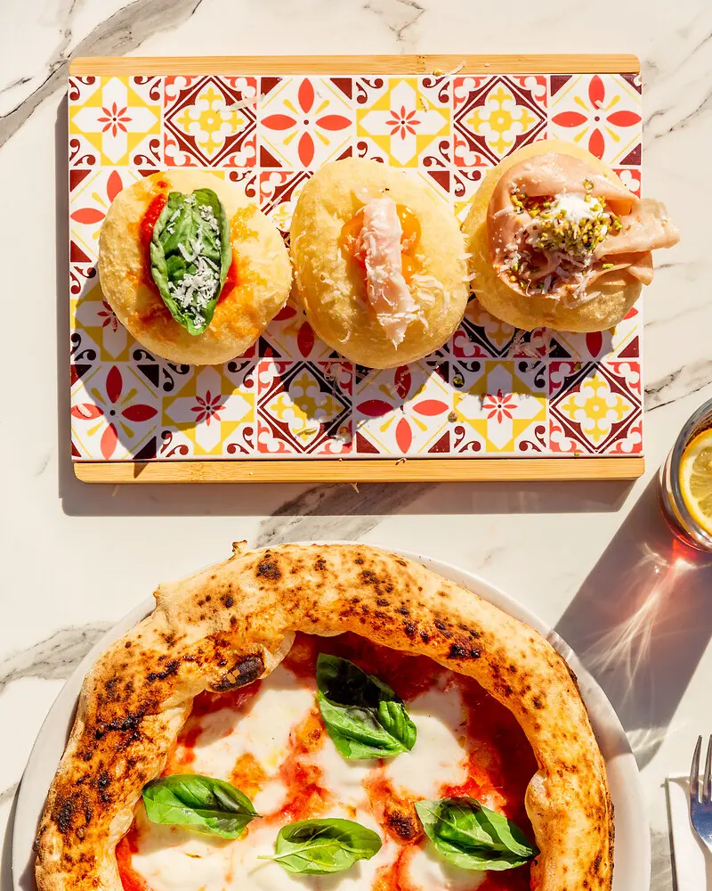 eine Pizza und drei Pizzabrötchen liegen auf Tellern serviert