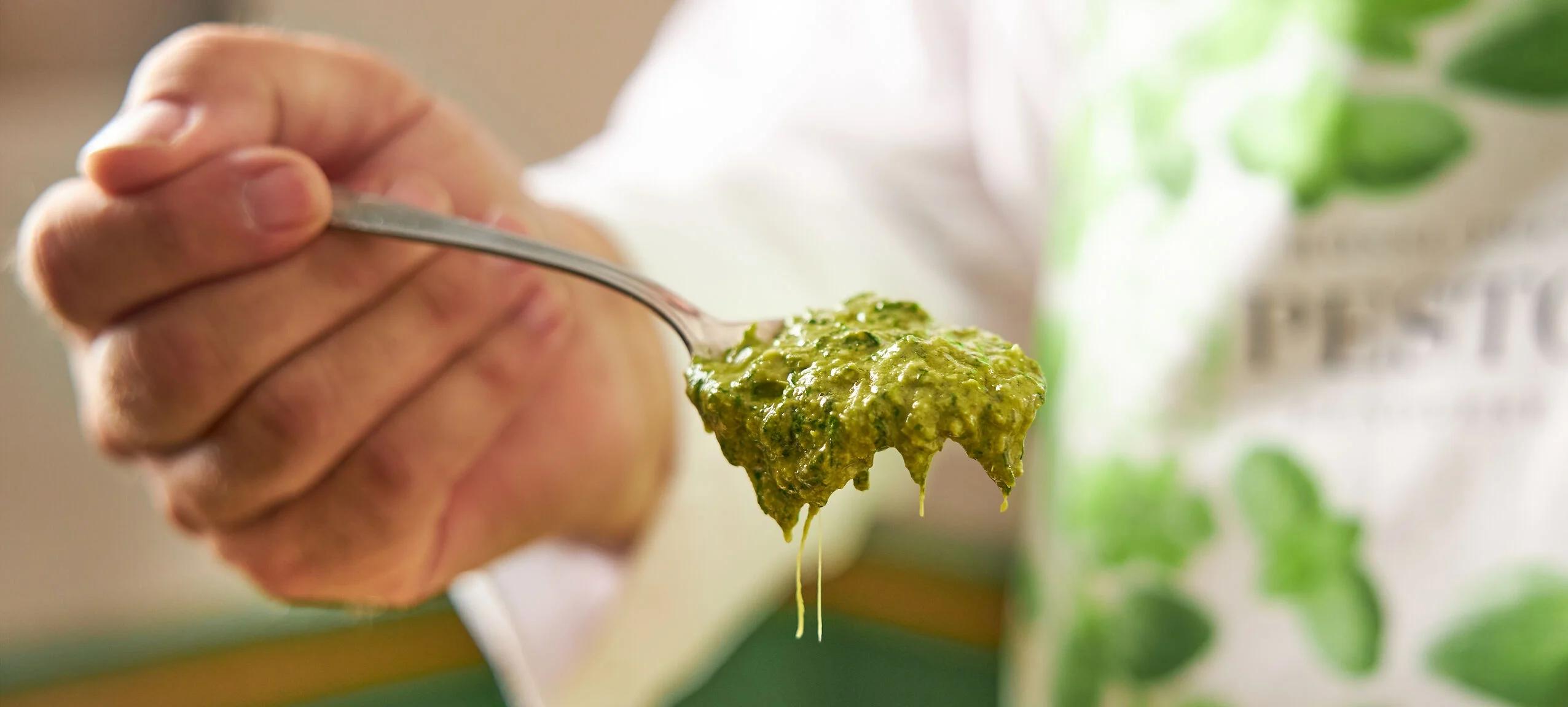 Hand hält einen Löffel mit Pesto Genovese D.O.P.