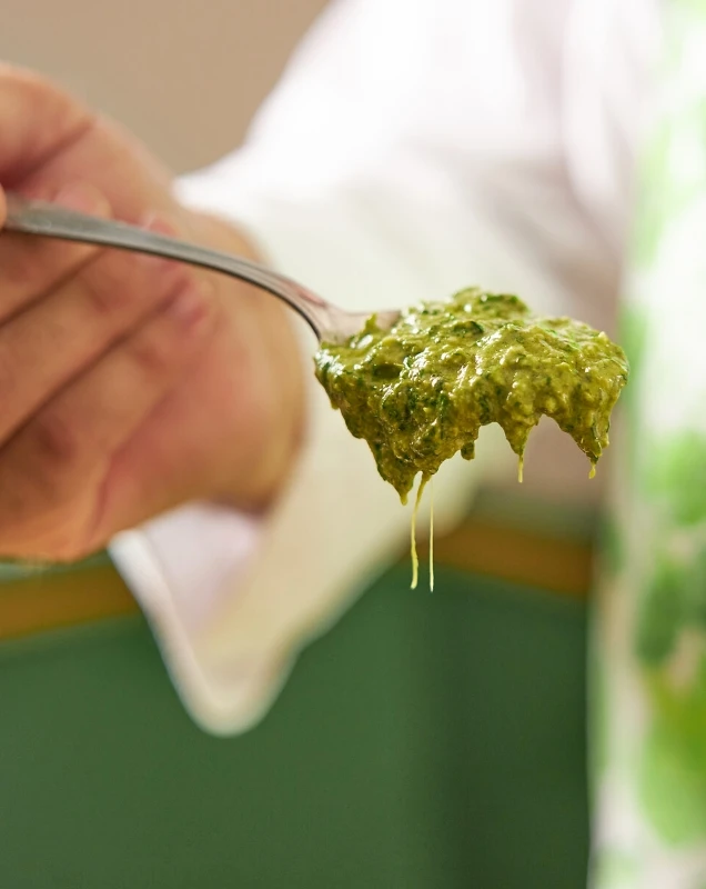 Hand hält einen Löffel mit Pesto Genovese D.O.P.
