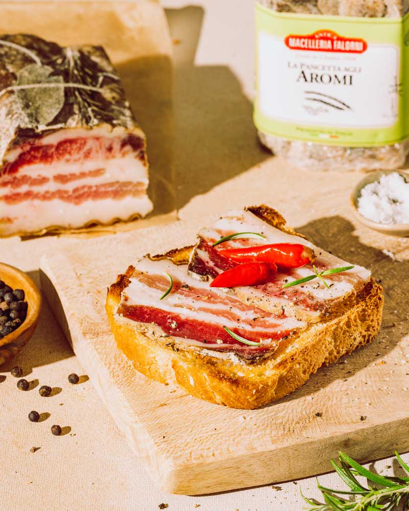 Pancetta mit Toskana-Kräutern - am Stück – mit passenden Accessoires arrangiert